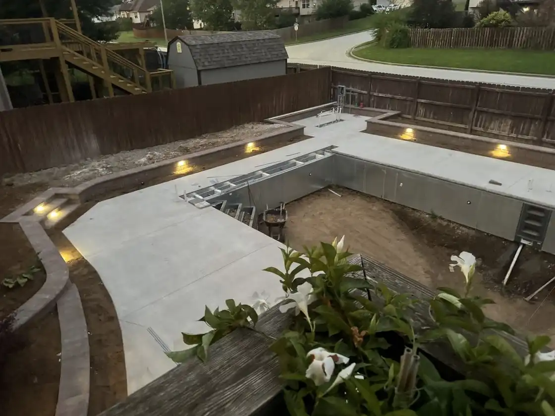 A pool deck at dusk with lights in the block planter walls, one of our jobs