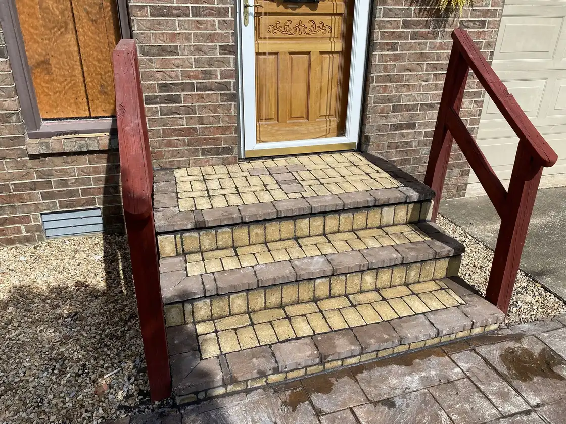 Paver steps with a railing at a front door, one of our jobs