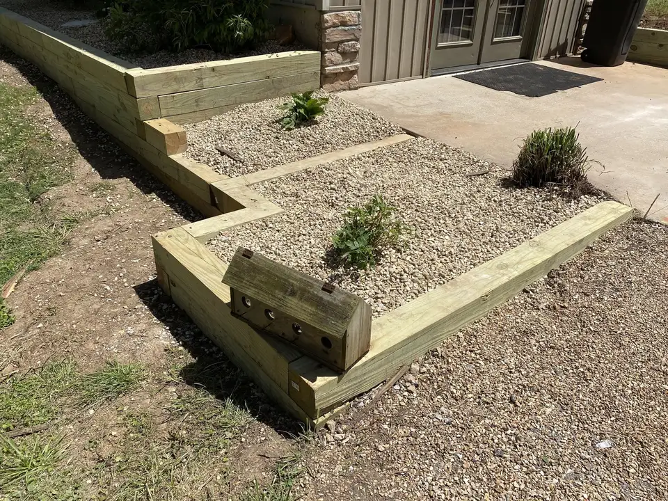 Timber-edged beds with gravel and plantings, one of our jobs